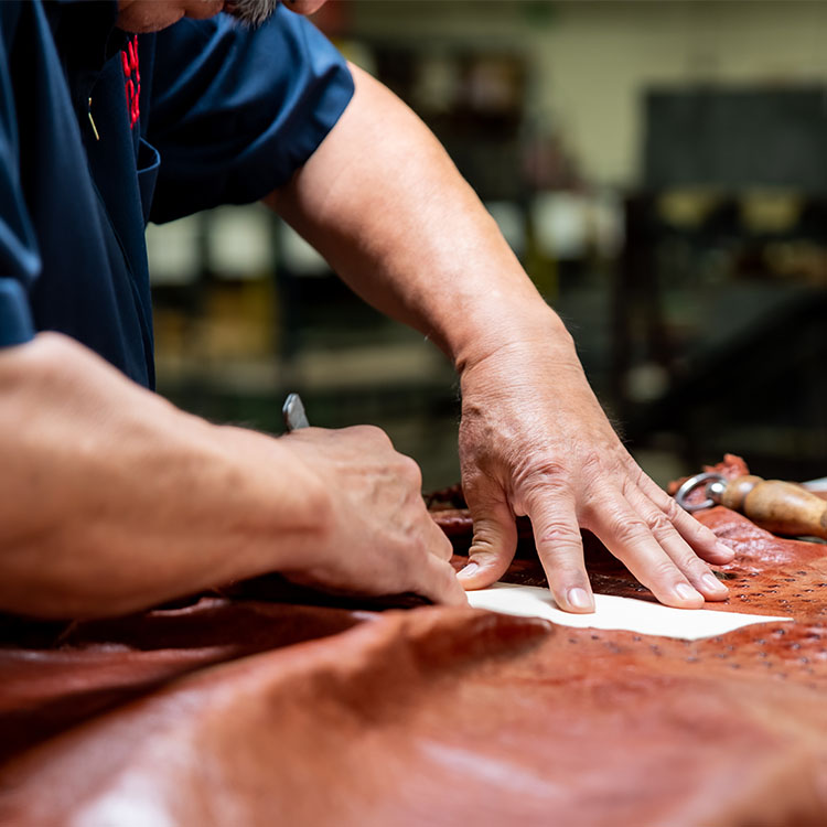 Man cuts exotic leather with knife.